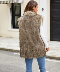 Outdoor street view of a long faux fox fur vest in natural brown-grey on a model
