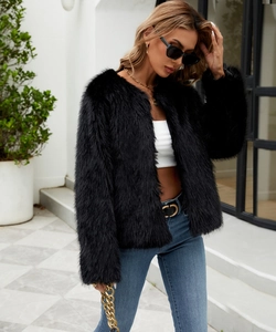 Detail of a chic black faux fur short jacket paired with a gold chain strap handbag