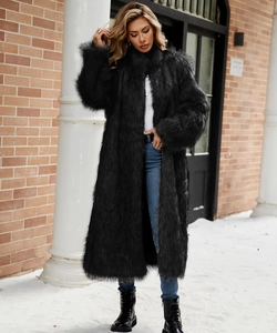 Vue complète d'un long manteau en fausse fourrure noire avec jean et bottes sous la neige