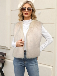 Outdoor street style shot of a beige faux fur vest paired with white long sleeve top
