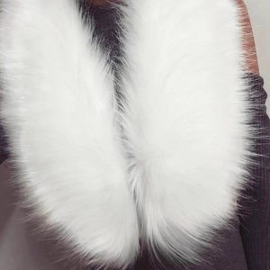 Col en fausse fourrure blanche à poils longs porté sur un pull de couleur sombre