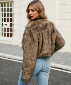 Outdoor street style shot of a woman in a shaggy tan faux fur jacket and blue jeans