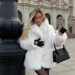 Close-up of white faux fox fur texture and luxury long coat details with black leather gloves