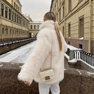 Rear view of long white faux fox fur coat with a plush texture in a winter scenic setting