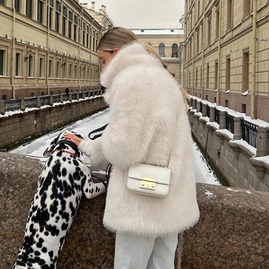 Detail of white faux fur coat with oversized lapel and matching chain shoulder bag