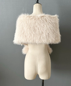 Close-up of beige faux fur shawl texture with fluffy pom-poms on a grey background