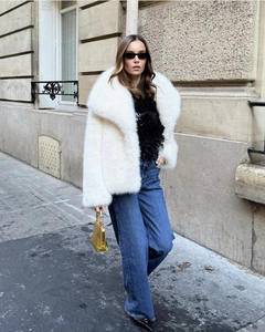 Détail d'une veste en fausse fourrure blanche à revers avec texture douce pour look de rue