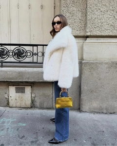 Détail d'un manteau en fausse fourrure blanche avec grand revers et texture douce