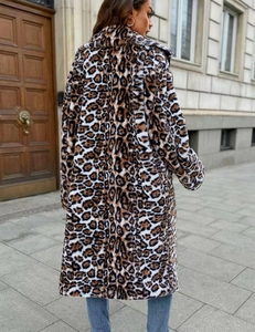 Outdoor street view of a woman wearing a long faux fur leopard print coat with lapel collar