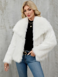 Detail of white faux fur coat featuring wide lapels and soft plush texture on outdoor model