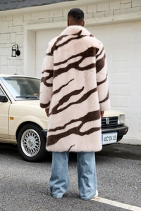 Outdoor street view of a men's long faux fur coat featuring a bold brown zebra pattern print