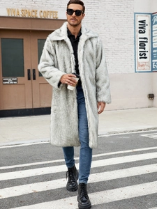 Outdoor street view of a luxury men's long faux fur coat in light grey and beige