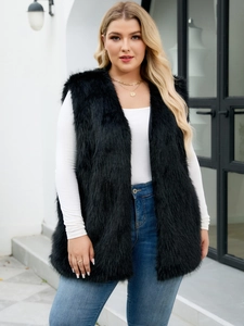 Close-up of black faux fur vest paired with white sweater and layered gold necklaces