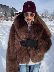 Detail of dark brown faux fur coat paired with a purple corduroy cap in a winter setting