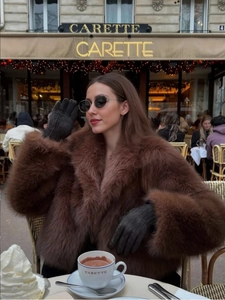 Detail of high-quality dark brown faux fur coat styled with black leather gloves