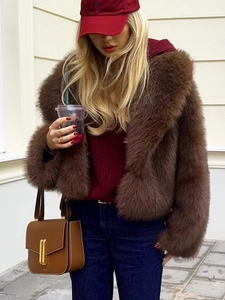 Close-up detail of dark brown faux fur jacket texture and gold buckle on leather handbag