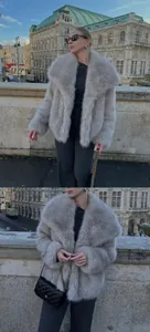 Detail of light gray faux fur coat with black knit set and quilted chain bag in urban street