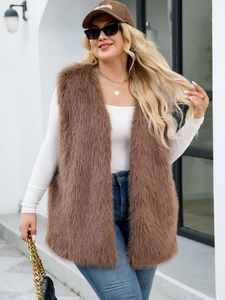 Outdoor street style shot of a long brown faux fur vest paired with white long sleeve top
