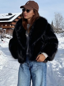 Detail shot of a black faux fur coat with a large lapel collar for winter fashion