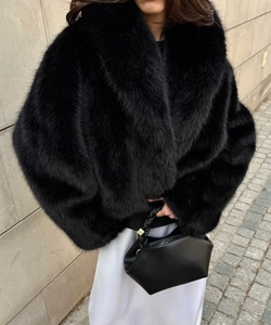 Close-up of black faux fur coat collar and geometric leather handbag with rope handle