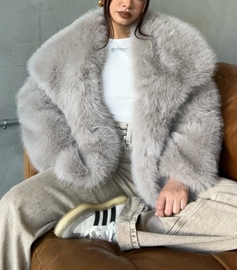 Detailed view of light gray faux fur coat with thick long pile texture and large lapel
