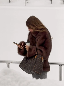 Detailed texture of thick dark brown faux fur coat with lapel collar in winter scenery