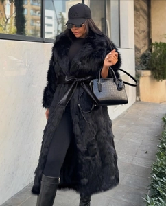 Détail d'un long manteau en fausse fourrure noire avec ceinture en cuir et texture riche