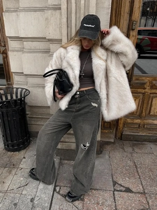 Plush white faux fur coat styled with wide-leg ripped jeans and a black baseball cap