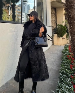 Style de rue d'un long manteau en fausse fourrure noire avec une large ceinture en cuir