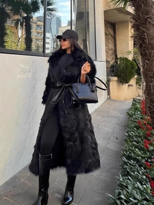 Manteau long chic en fausse fourrure noire avec ceinture en cuir et bottes hautes