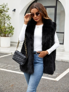 Close-up of black faux fur vest paired with white top and gold coin necklace