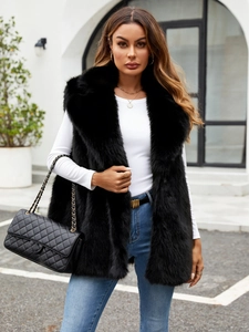 Chic black faux fox fur vest with stand collar over a white long-sleeve top and blue jeans