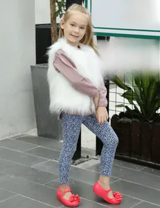 Vue détaillée d'un gilet en fausse fourrure blanche pour enfant avec un haut rose doux