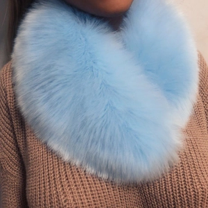 Detailed view of fluffy sky blue faux fox fur collar scarf on a brown sweater
