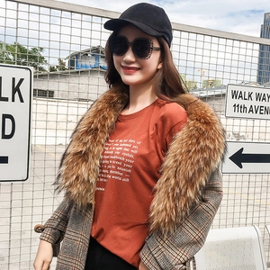 Detail of a thick brown faux fur collar on a grey plaid coat and orange graphic tee