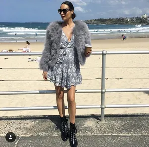 Vista street style di una giacca corta grigia in piume di struzzo e abito floreale