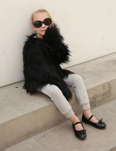 Detail of premium fluffy black faux fur coat for girls with long dense plush texture