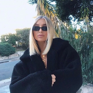 Close-up of black fuzzy lamb wool hooded jacket with stylish oversized fit and cozy texture