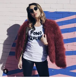 Giacca corta in ecopelliccia color bordeaux con t-shirt bianca e occhiali da sole neri