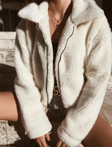 Detailed texture of white teddy jacket fabric with fuzzy collar and black zipper