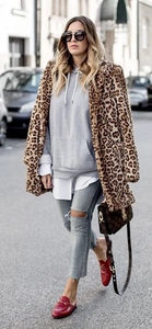 Street style detail of a leopard print faux fur coat paired with denim and red mules