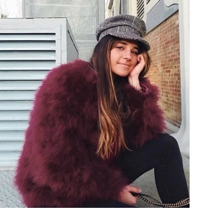 Cappotto bordeaux in pelliccia sintetica con berretto piatto in un contesto urbano