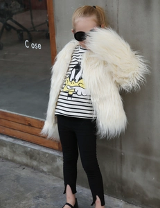 Close-up of kids cream faux fur coat with striped T-shirt and black split-leg trousers