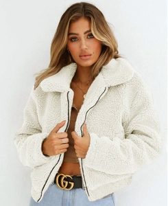 Close-up of white teddy jacket with faux lamb fur texture and contrasting black zipper detail