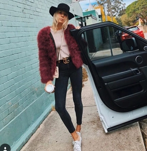 Scatto street di una giacca in finta pelliccia bordeaux con cappello nero e fibbia d'oro
