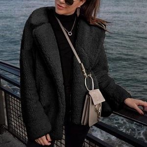 Outdoor shot of a black faux fur coat featuring a large lapel and teddy fleece texture