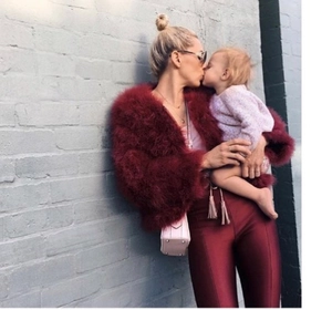 Giacca corta in ecopelliccia bordeaux alla moda con pantaloni lucidi e scena di vita reale