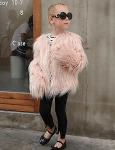 Outdoor street style view of a pink faux fur coat for girls with fluffy long texture