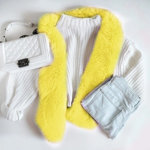 Vista flat lay di collo in ecopelliccia gialla con maglione bianco e jeans azzurri