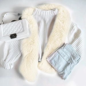 Dettaglio di un soffice collo in ecopelliccia cucito su un maglione bianco